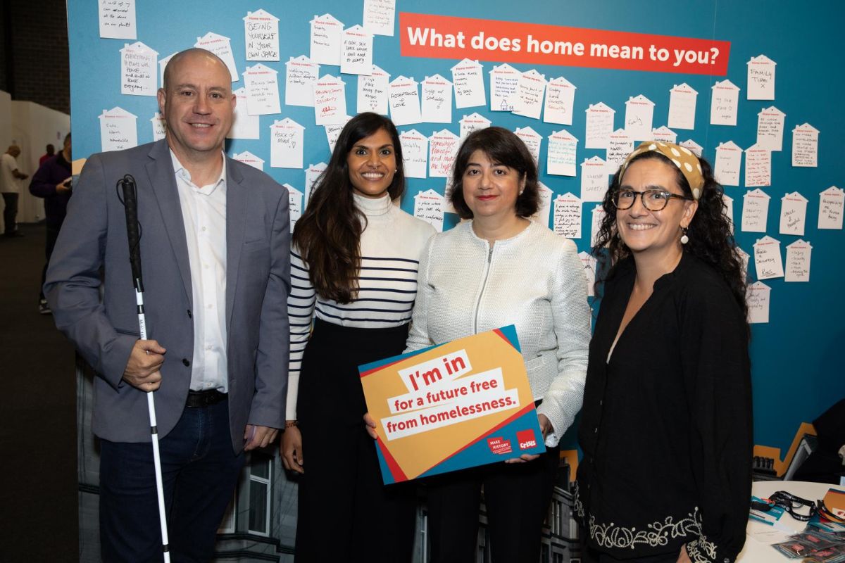 Three women and a man with a white can stand in front of a conference display