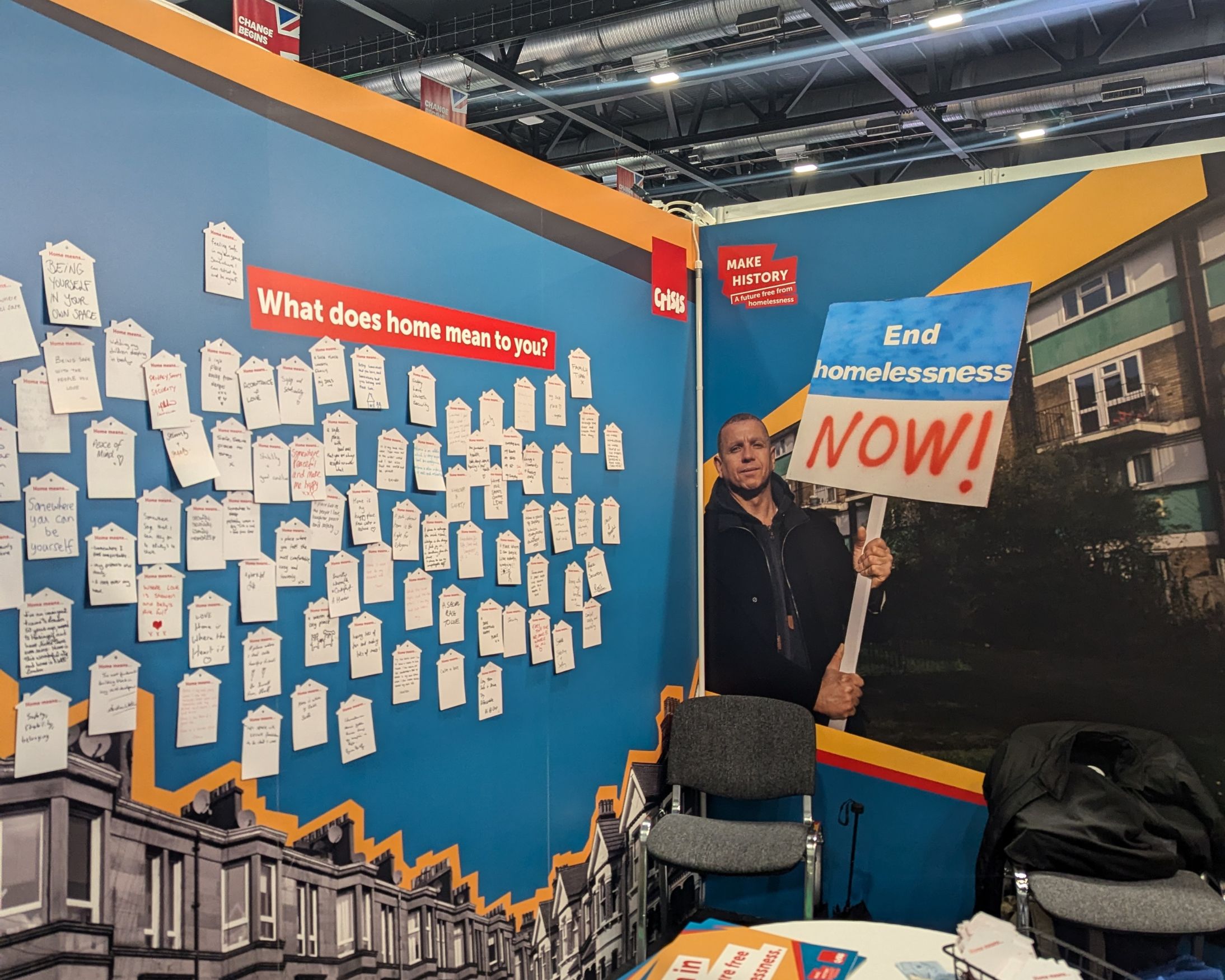 A conference stand showing small paper houses with messages about the meaning of home written on them